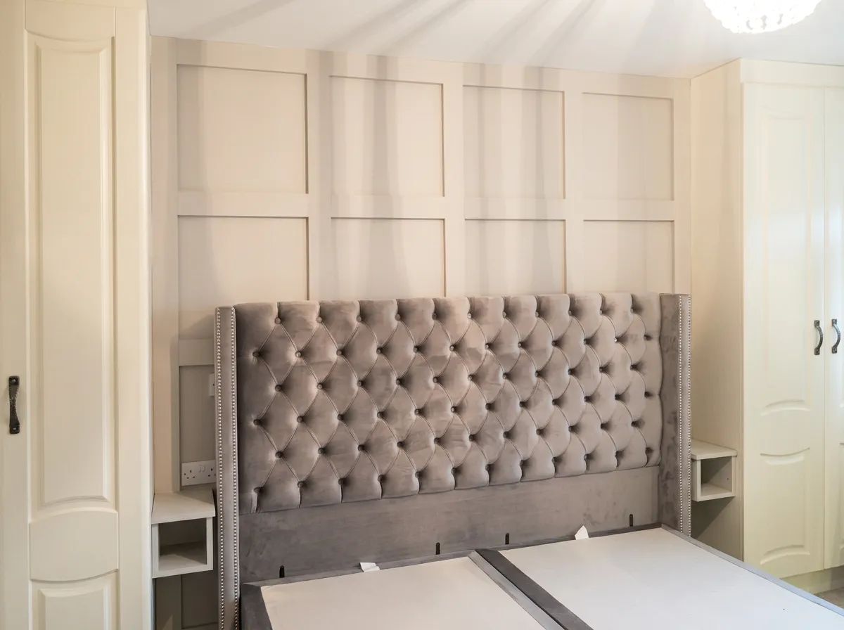 Bedroom feature wall in square panelling behind the bed, with fitted wardrobes on either side
